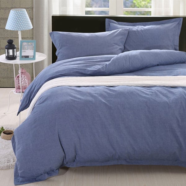 A bed with blue sheets and pillows on it