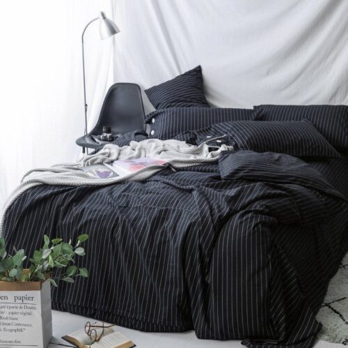A bed with black sheets and pillows on it