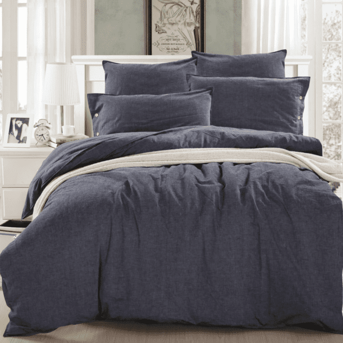 A bed with dark blue sheets and pillows.