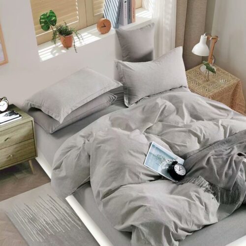A bed with grey sheets and pillows on it