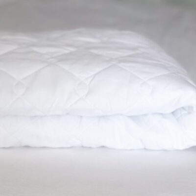 A close up of the white cover on a bed