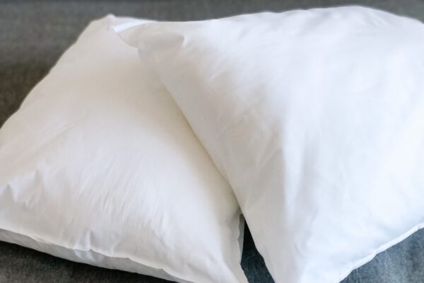 Two white pillows on a bed with one pillow in the middle.