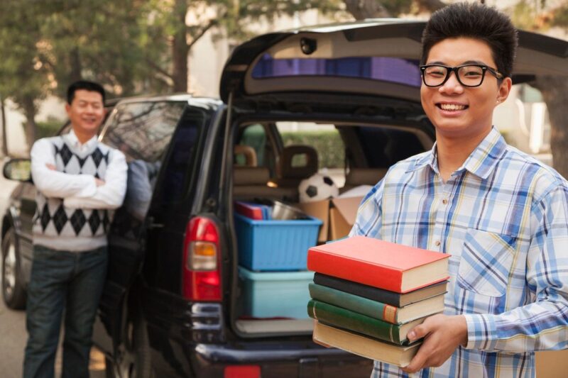 student unpacking car holding books