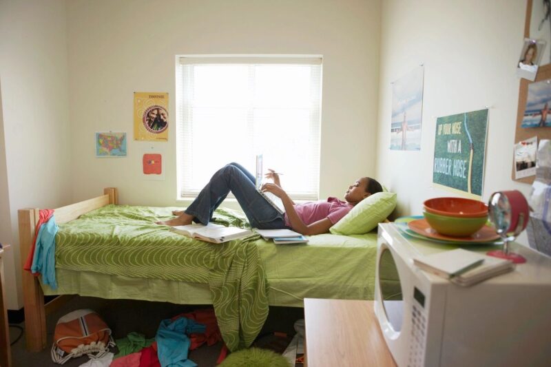 student lying on bed in dorm room